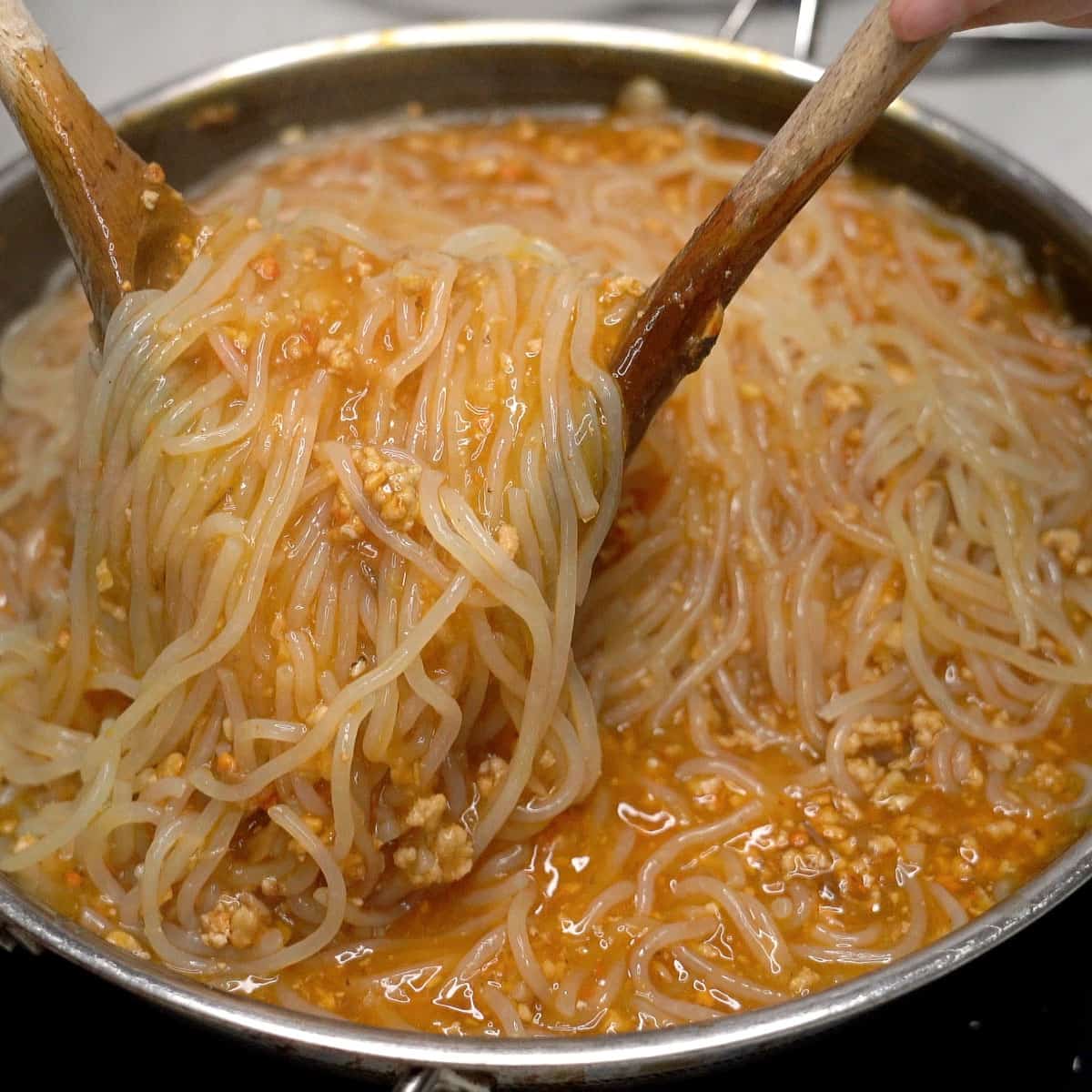 Tossing the noodles with the sauce in the wok.
