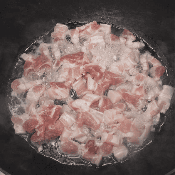 Pork belly simmering in a wok.