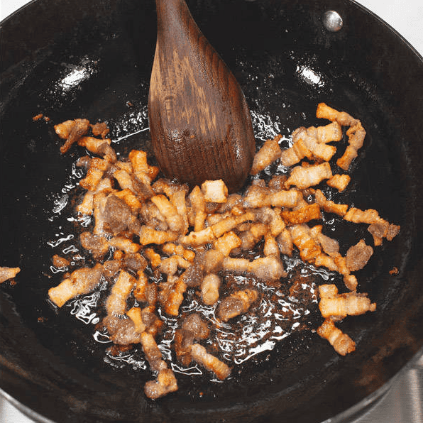 Browning pork belly in a wok.
