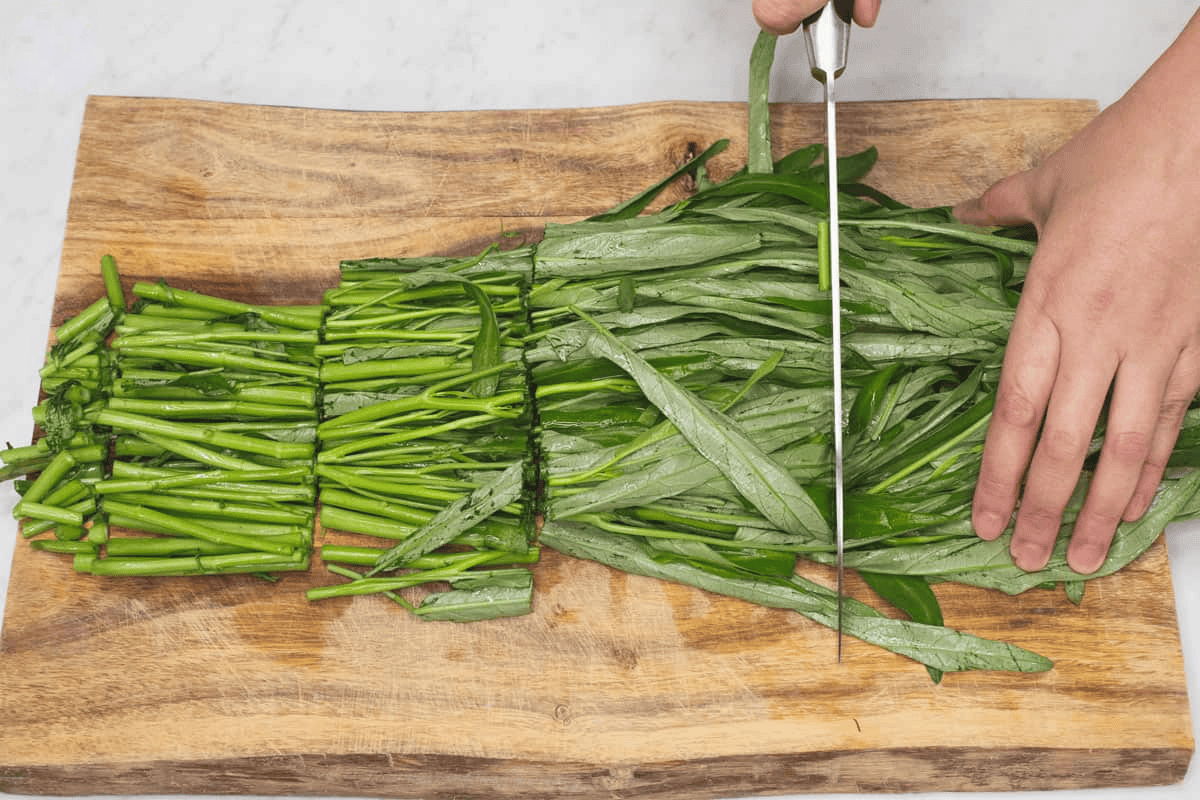 Cutting the kangkong into small sections.