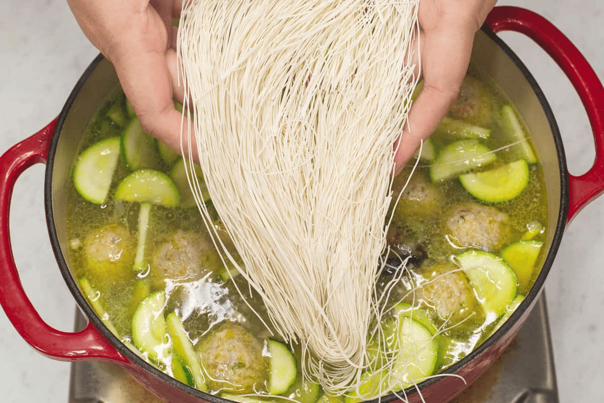 Adding the misua (wheat vermicelli) into the mixture in the pot.