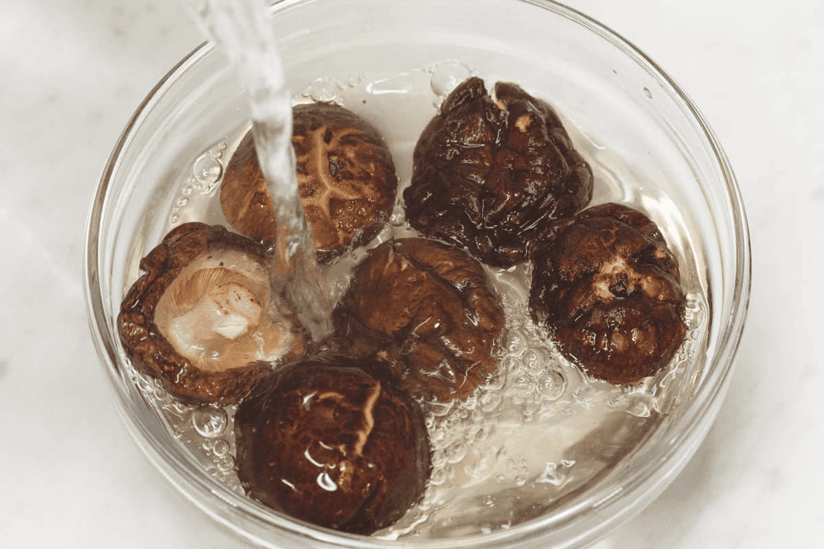 Adding water to the shiitake mushrooms in the bowl.