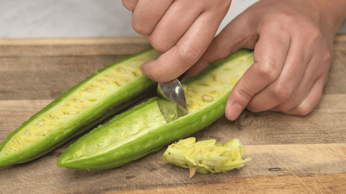 Scooping out the seeds and white pith from the bitter melon half.