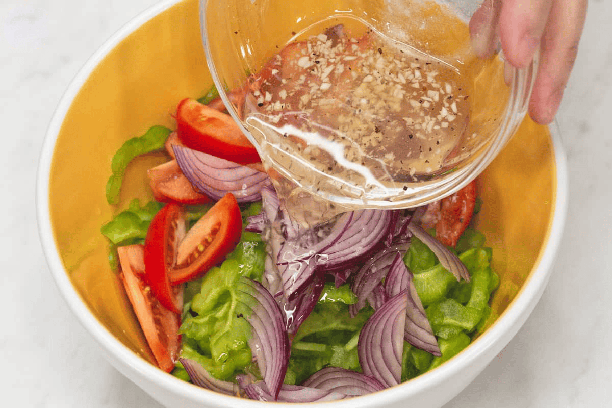Pouring the dressing over the salad ingredients.