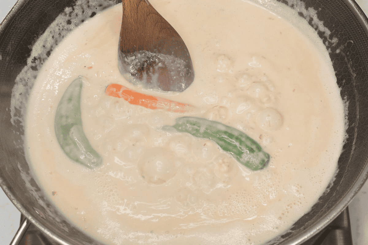 Simmering the coconut milk and whole chilies in the wok.