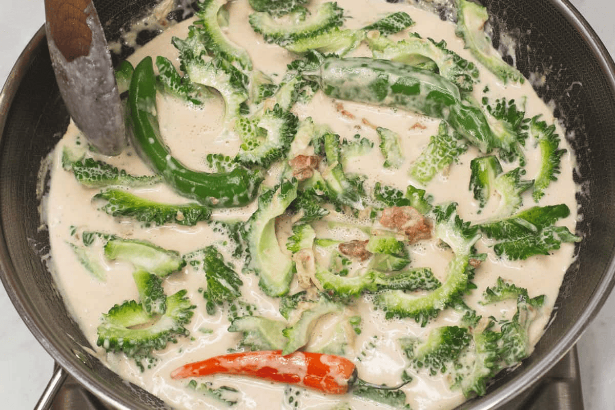 Ampalaya and other ingredients with the coconut milk in the wok.