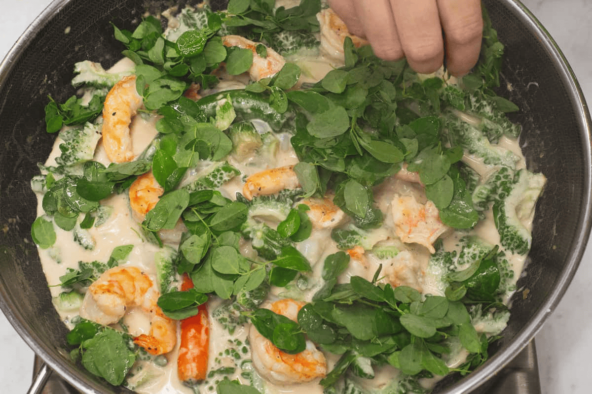 Adding the malunggay leaves to the mixture in the wok.