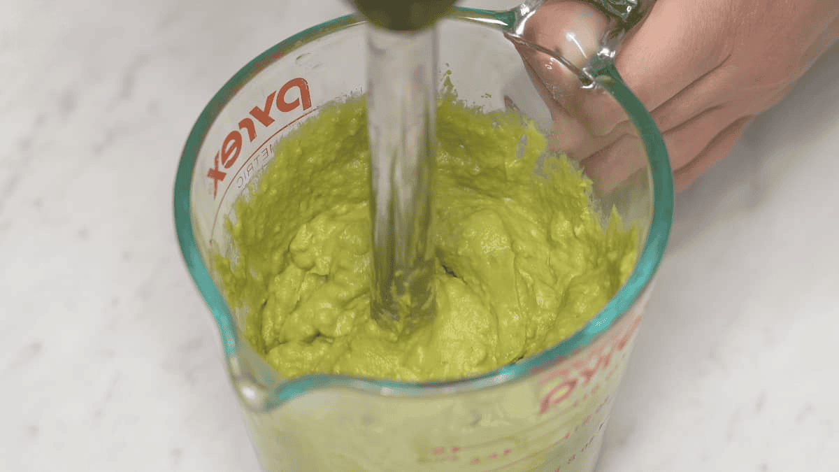 Blending the avocados in a cup using an immersion blender.