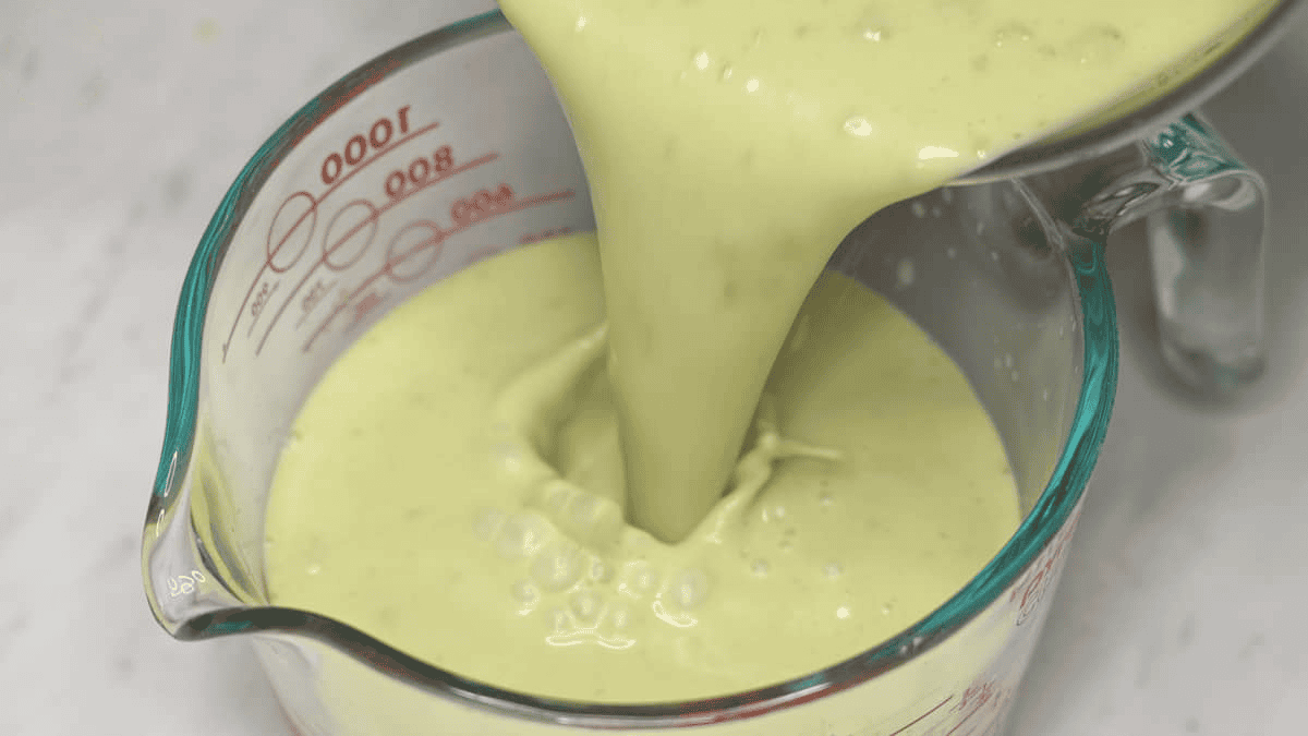 Pouring the base for Avocado and Pistachio Ice Cream in a container.