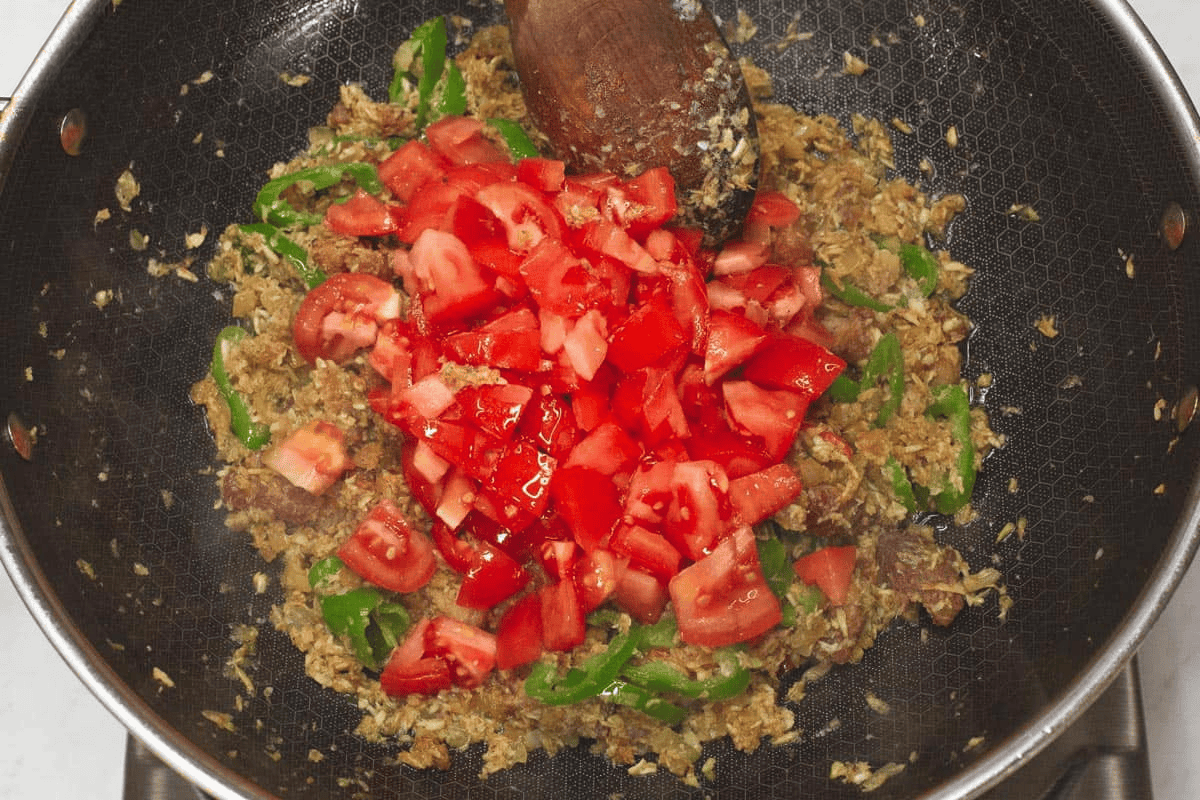 Added tomatoes to the shrimp paste mixture in the wok.