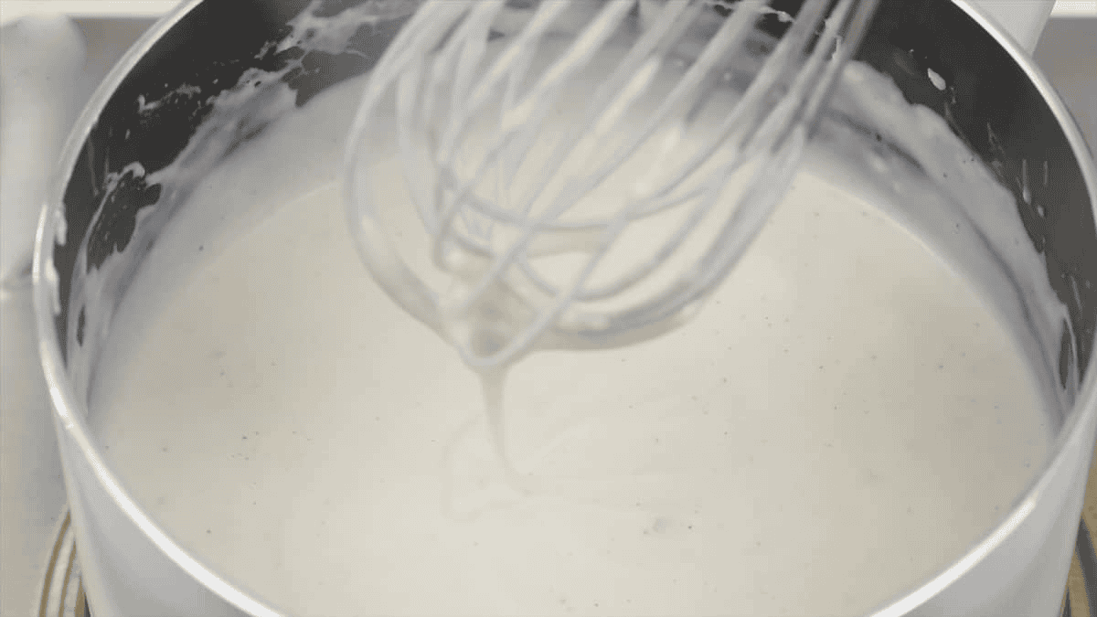 Whisking the bechamel sauce in the saucepan.