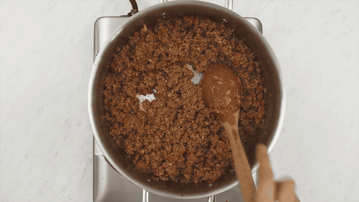 Browning the ground beef in the pan with aromatics and tomato paste.