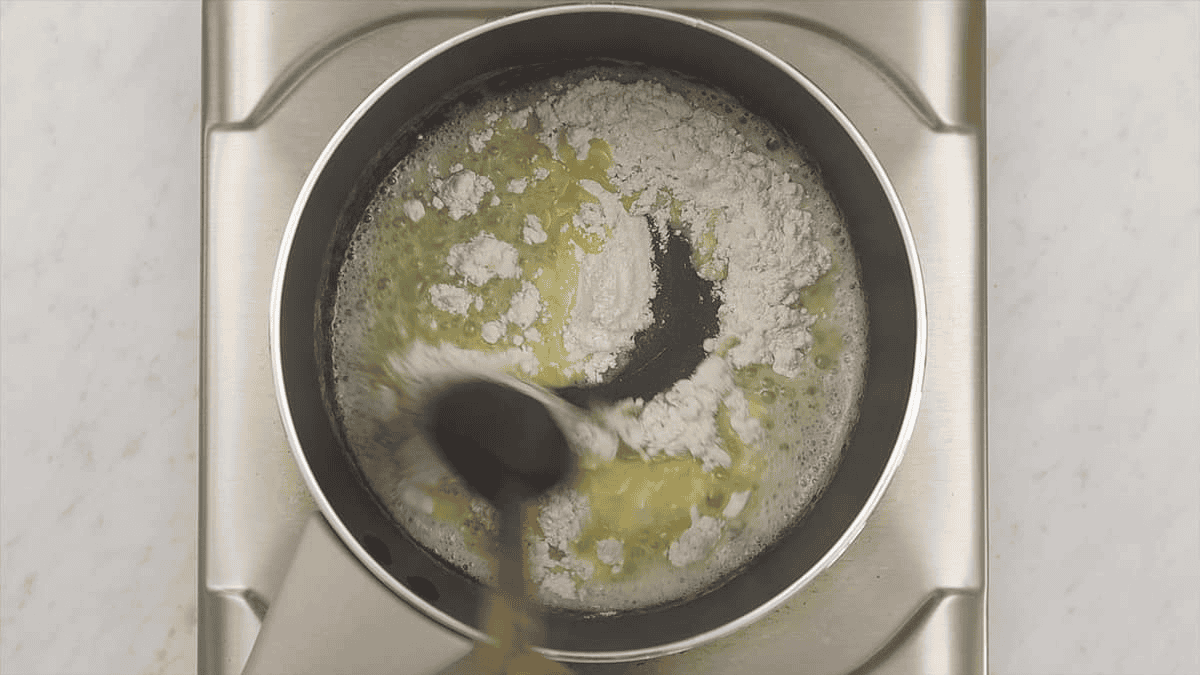 Mixing melted butter and flour in a saucepan.