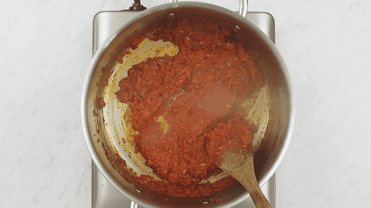 Sauteing tomato paste with aromatics in the saute pan.