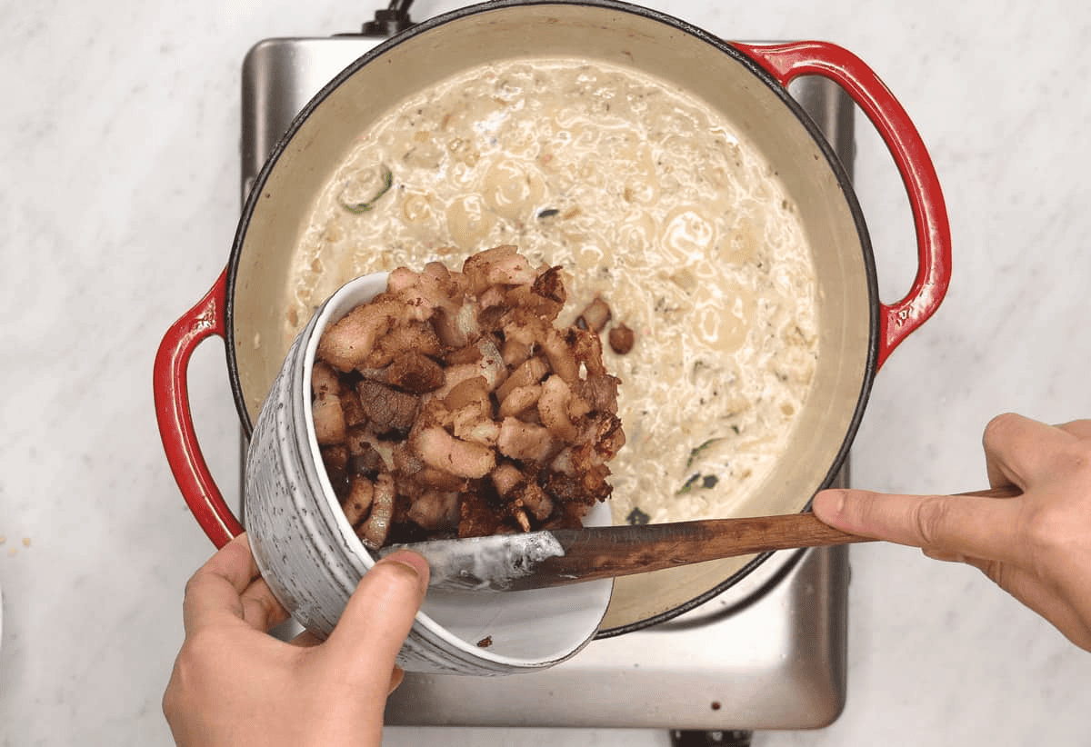 Adding the browned meat to the pot.