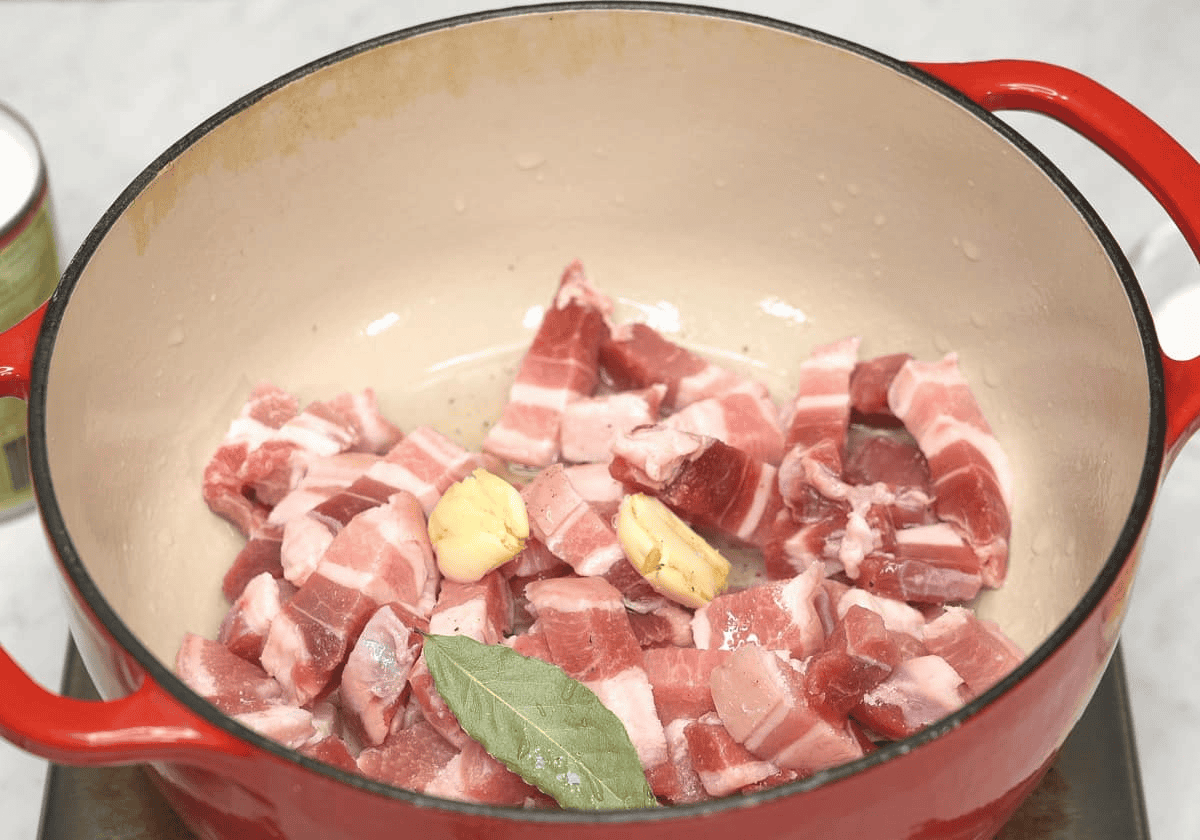 Pork and aromatics in a Dutch oven.