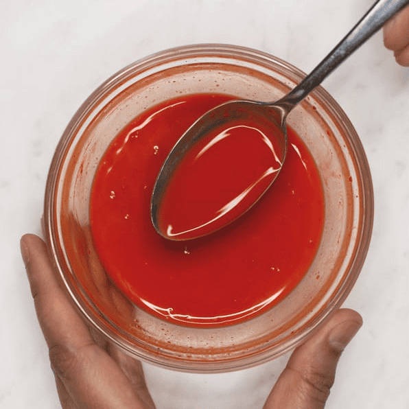 Dissolving annatto powder in a small bowl.