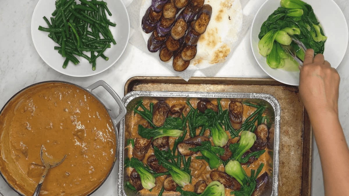 Arranging Big Batch Kare-Kare with Beef (in Peanut Sauce) in an aluminum pan.