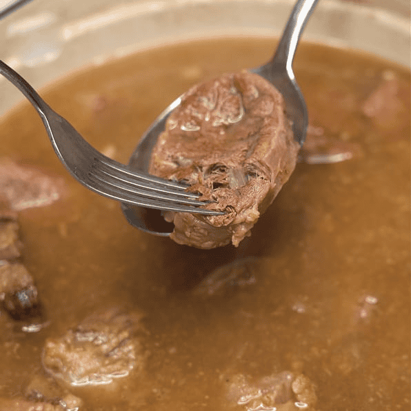 Checking a piece of beef for tenderness with a fork.