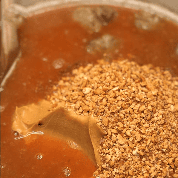 Adding peanut butter and ground peanuts to the sauce.