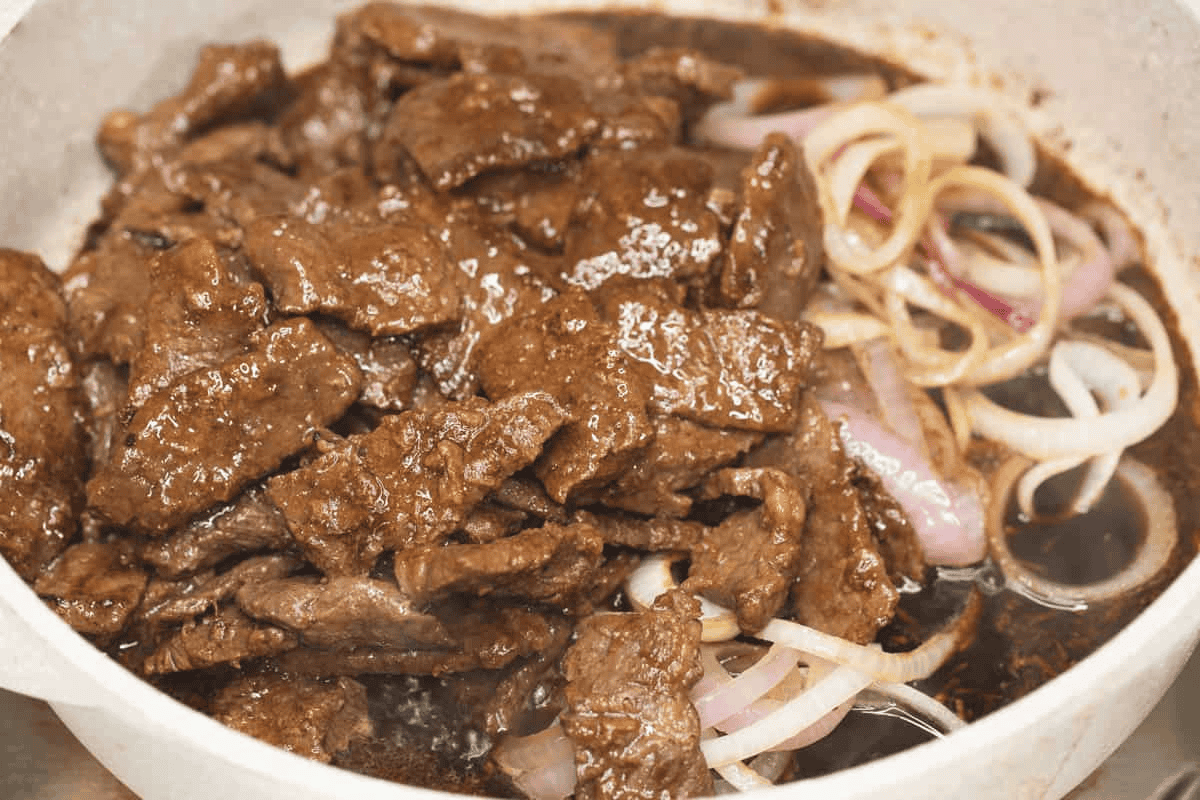 Added the seared onions and beef to the sauce in the saute pan.