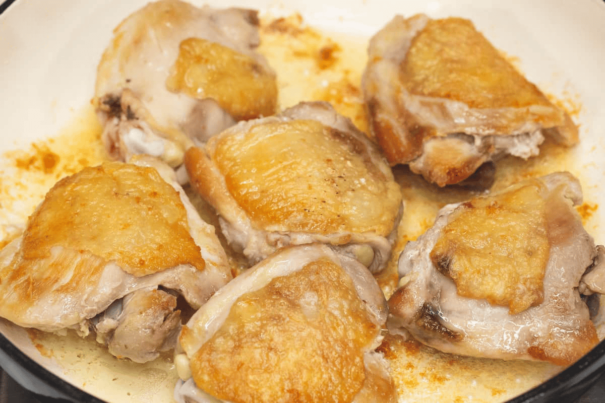 Seared chicken thighs on a saute pan.