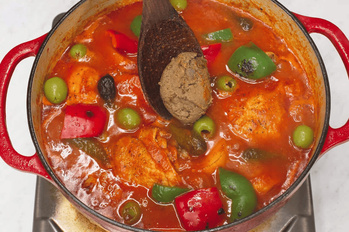 Adding liver spread to the Chicken Caldereta in the pot.