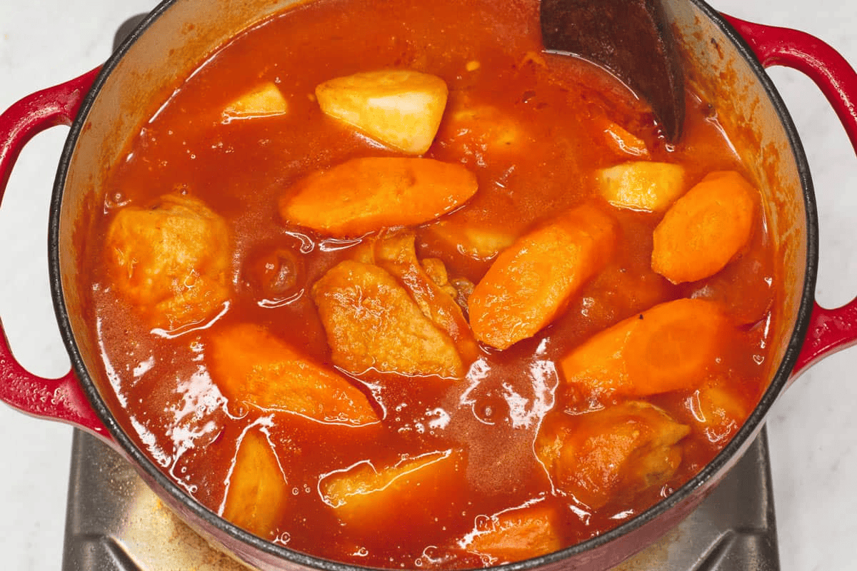 Mixing the Chicken Caldereta in the pot.