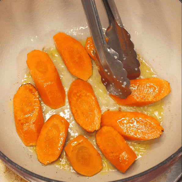 Searing sliced carrots in a pot.