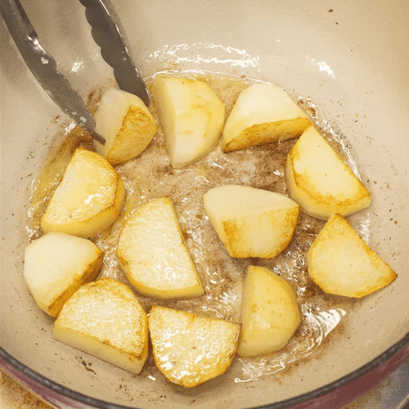 Searing potato pieces in a pot.