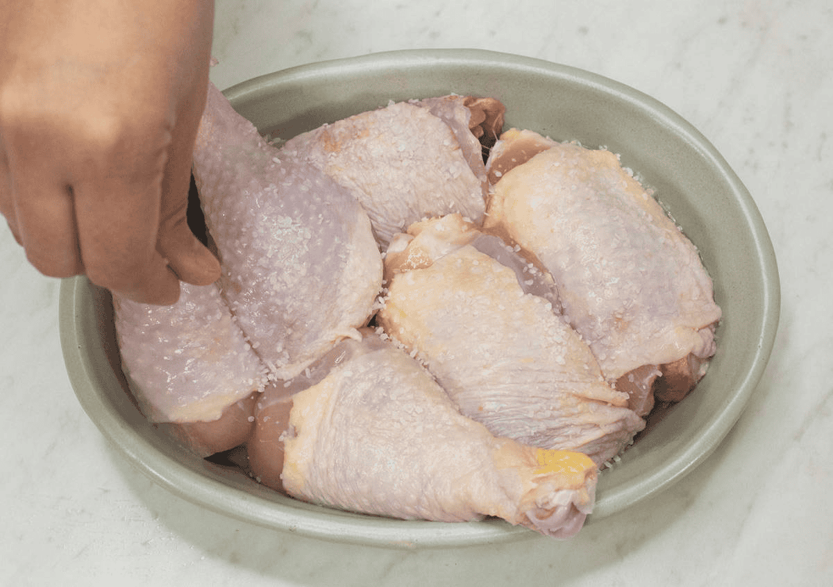 Seasoning the chicken with salt.