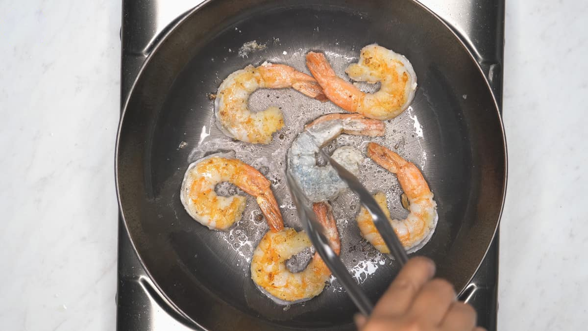 Searing the shrimp in the pan.