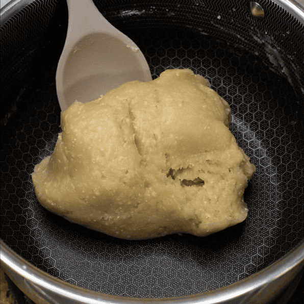 Stirring churros dough until it forms a smooth ball.
