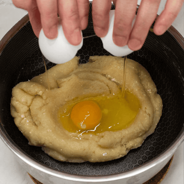 Cracking an egg into the churros dough.
