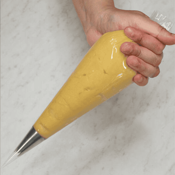 Holding a filled piping bag fitted with a star tip.