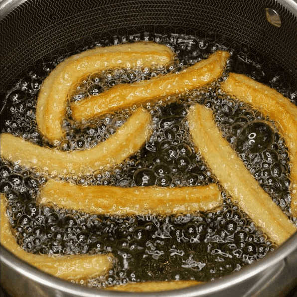 Frying churros in hot oil until golden brown.