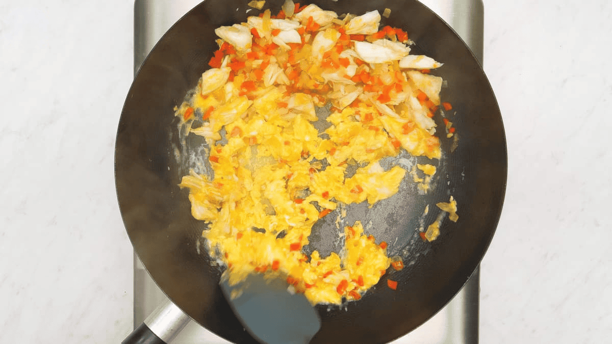 Scrambling eggs in the wok with crabmeat and aromatics.