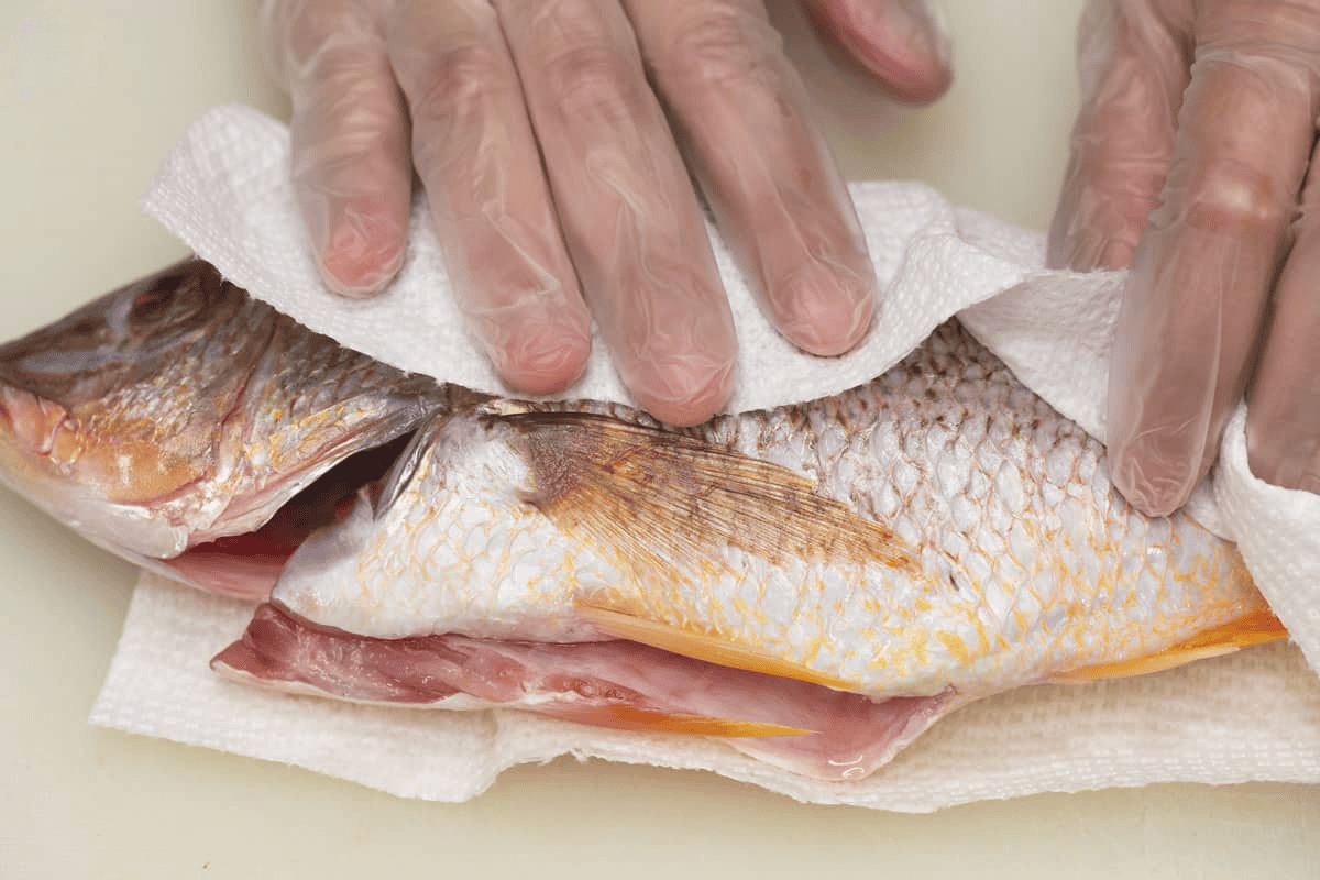 Patting the fish dry with a paper towel.