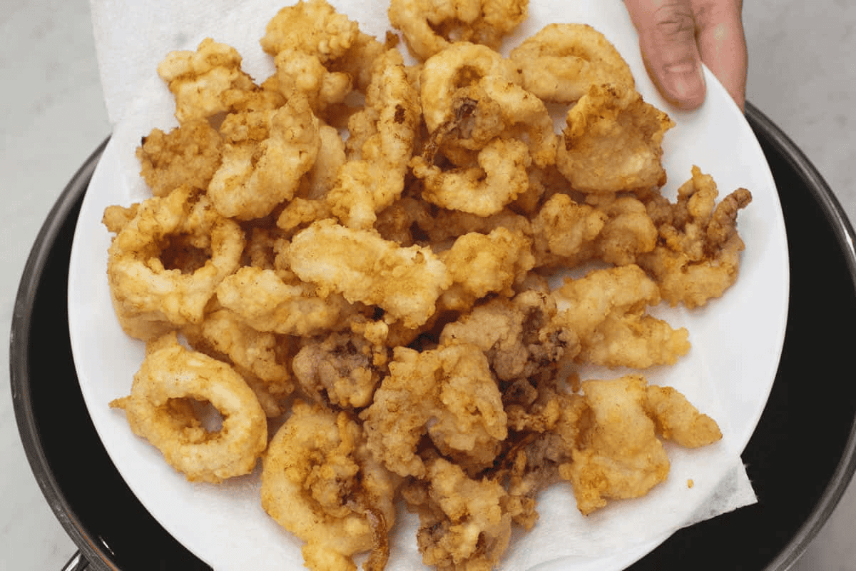 Fried squid on a paper towel-lined plate.