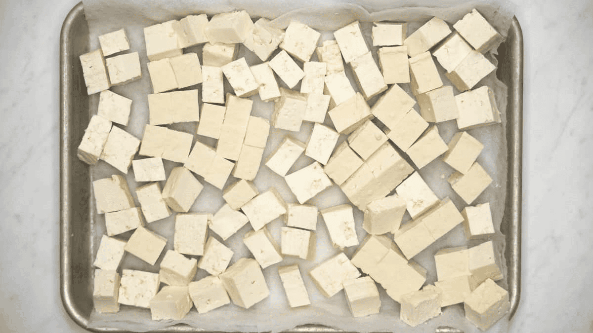 Drying tofu cubes on a paper towel-lined baking sheet.