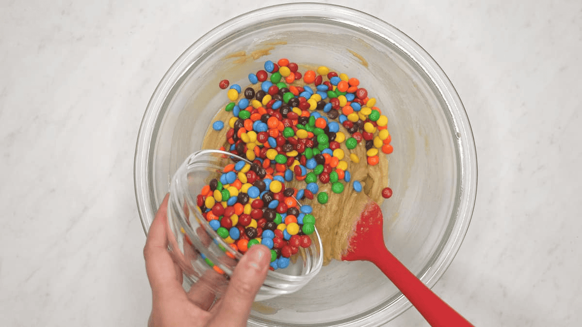 Folding M&Ms into the cookie dough.