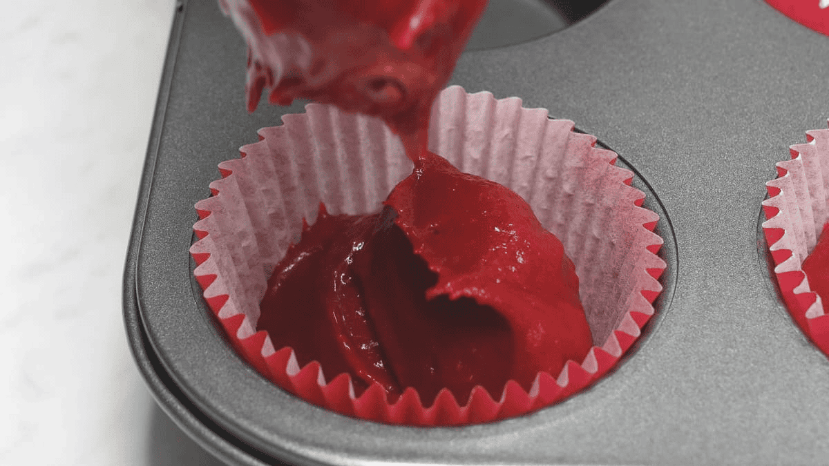 Red velvet cupcake batter in cupcake liners.