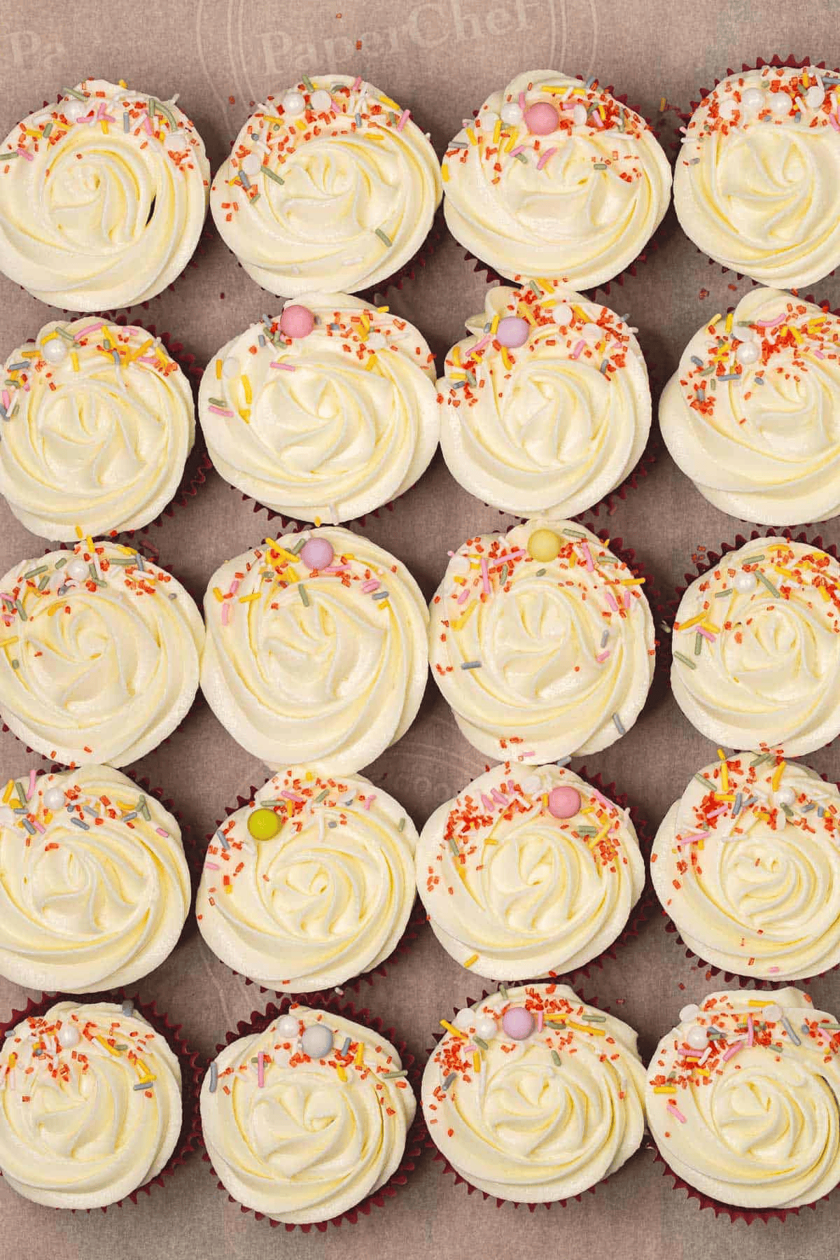 Red Velvet Cupcakes with cream cheese frosting and sprinkles on parchment paper
