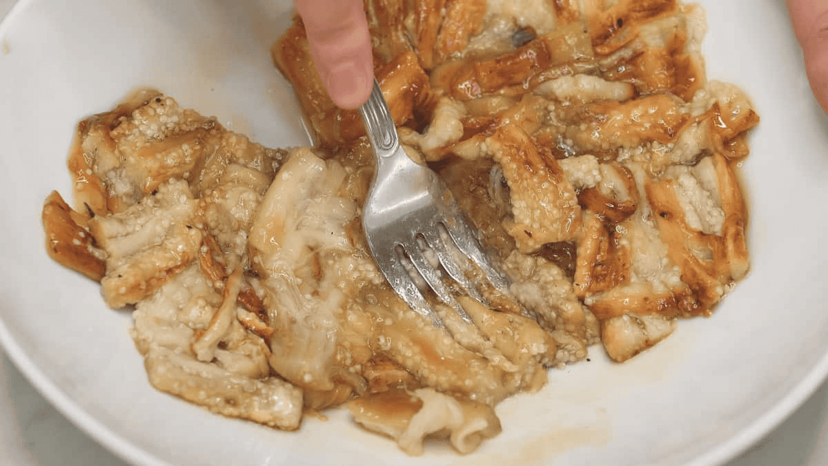 Mashing the eggplant with a fork in a bowl.