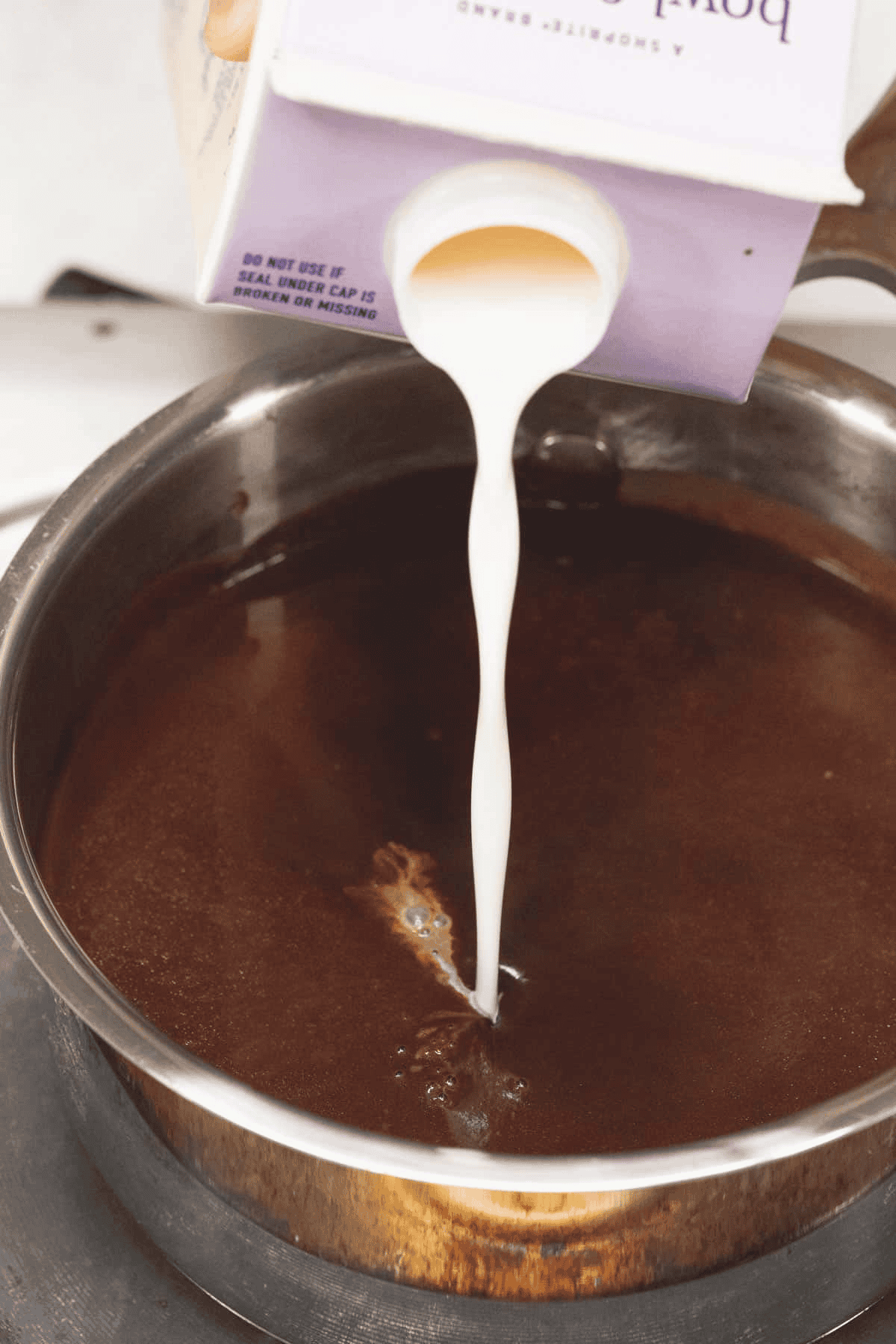 Adding the dairy to the hot chocolate in the saucepan.
