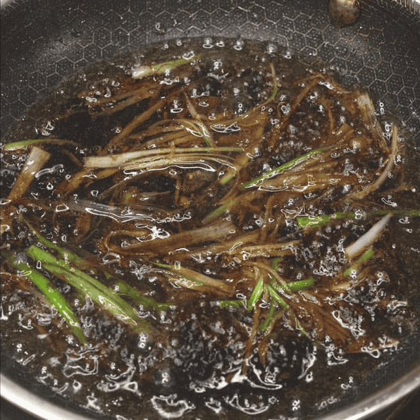 Simmering the ginger and scallion sauce in a skillet.