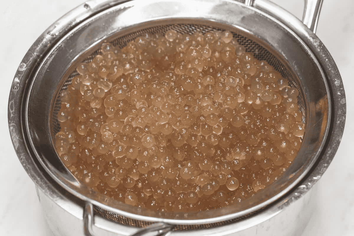 Cooked sago in a strainer over a saucepan.