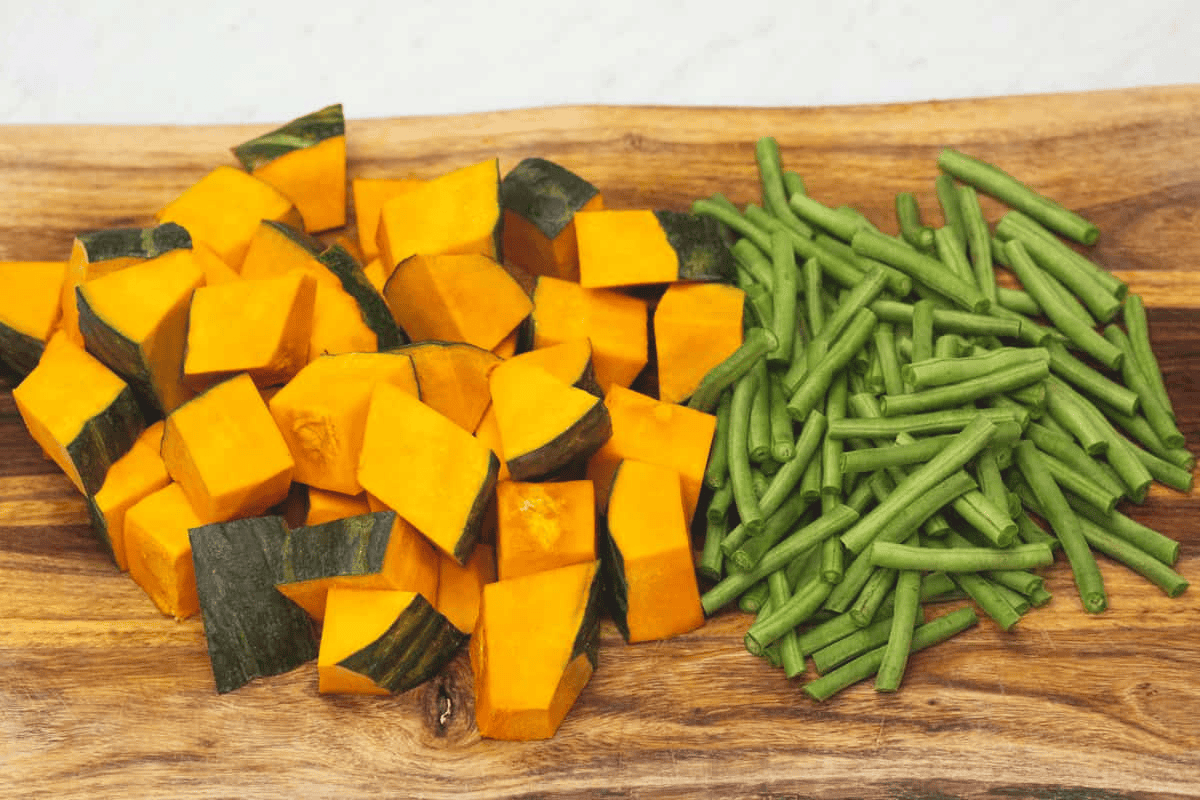 Cut kabocha squash and yardlong beans on a cutting board.