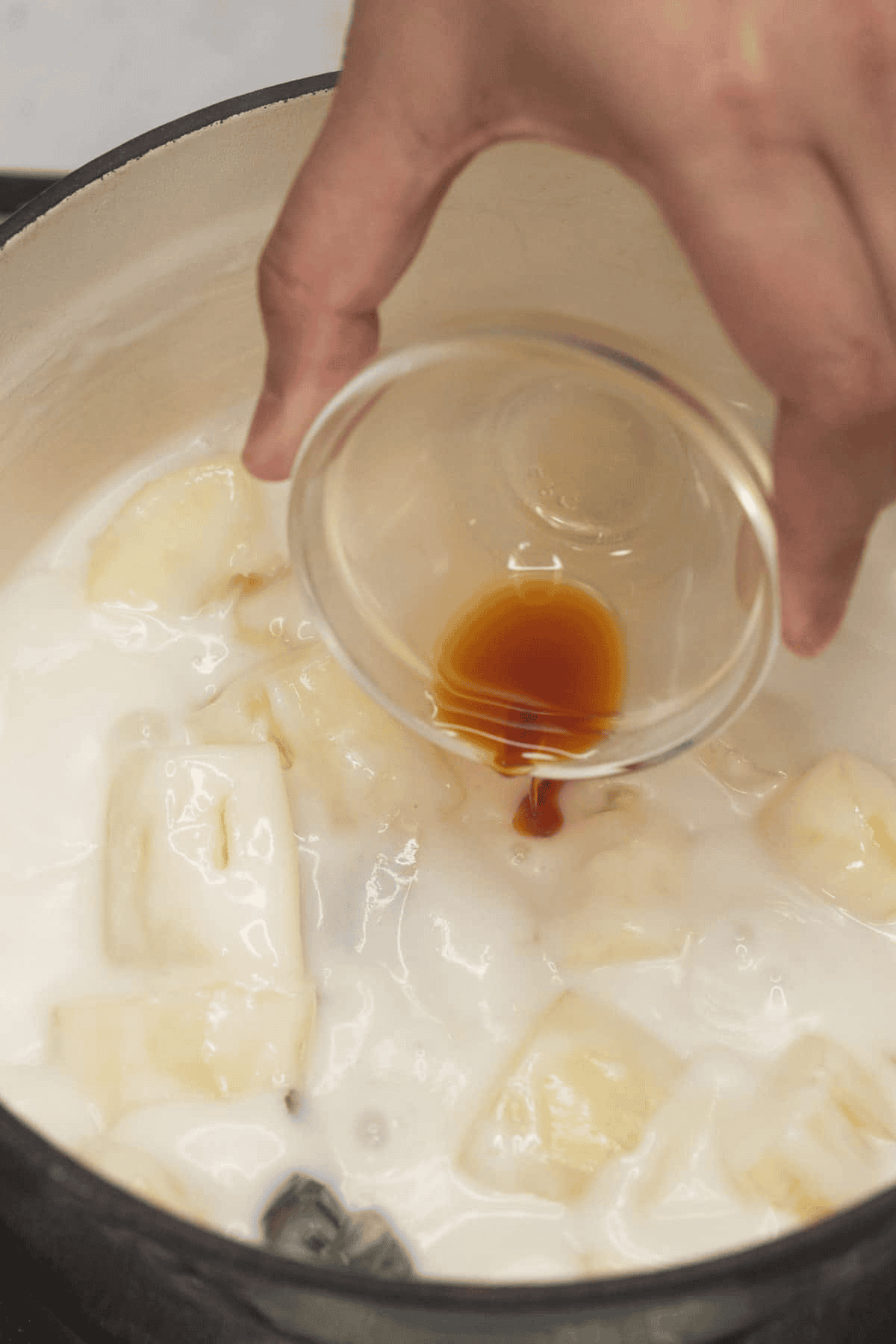 Adding vanilla extract to Ginataang Kamoteng Kahoy (Cassava with Coconut Milk).