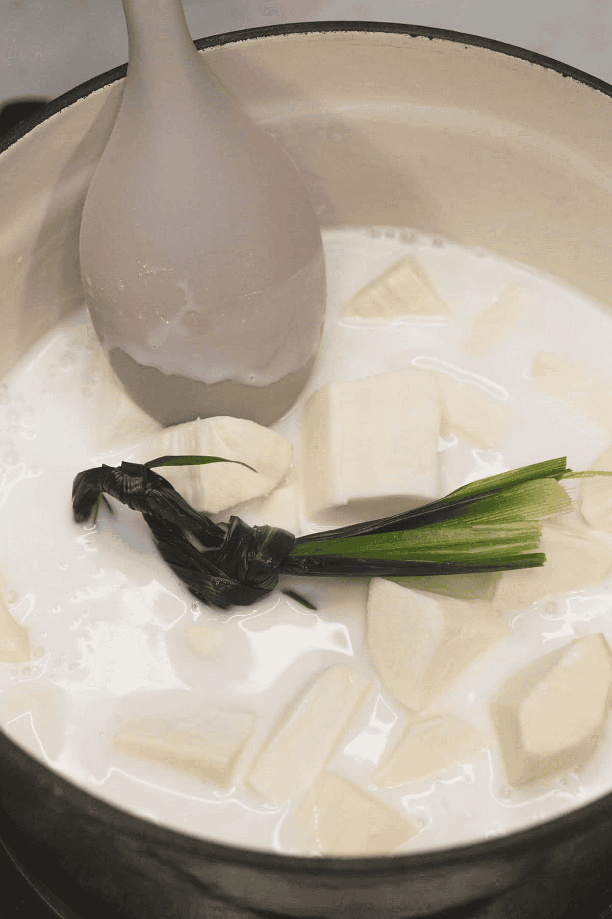 Combining the ingredients for Ginataang Kamoteng Kahoy (Cassava with Coconut Milk) in the pot.